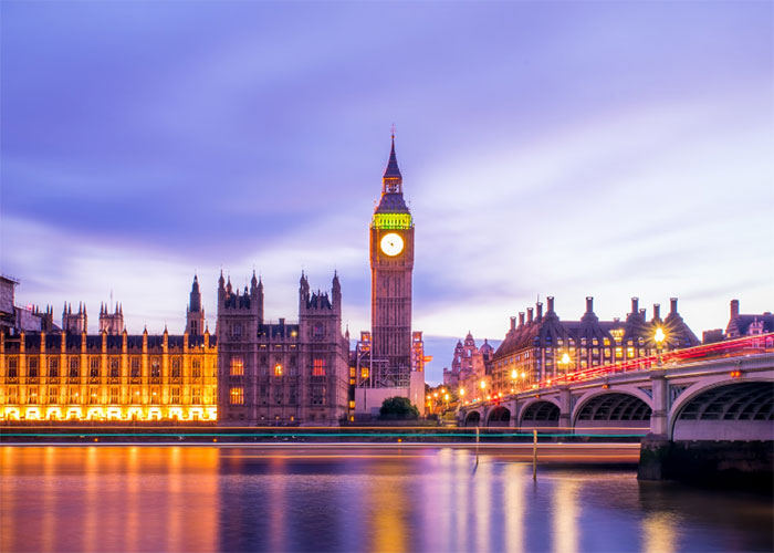 Big Ben and the Houses of Parliament in the UK illuminated during twilight, with reflections shimmering on the River Thames